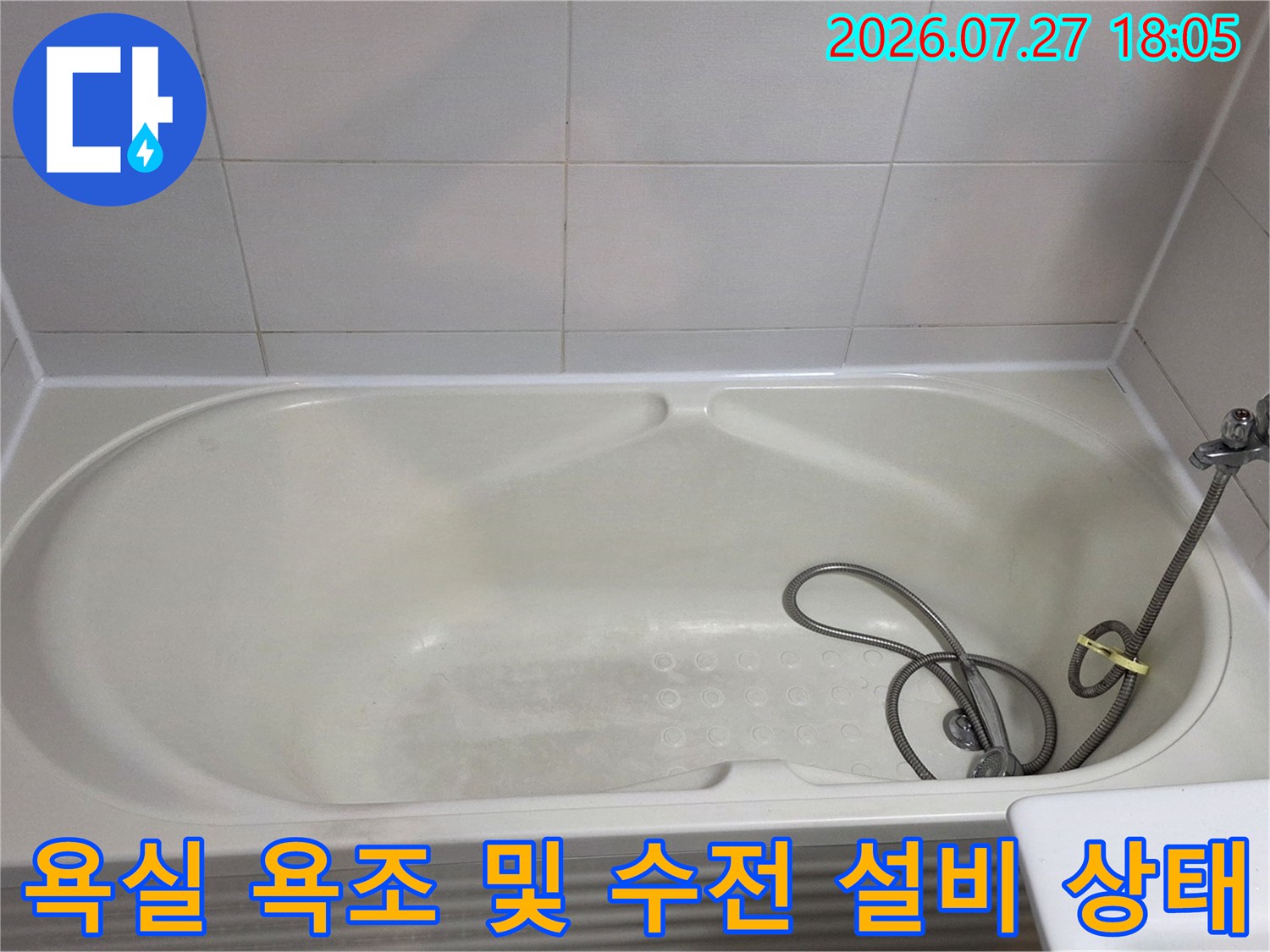 샤워 호스가 연결된 수전과 흰색 아크릴 욕조가 배치된 화장실 모습