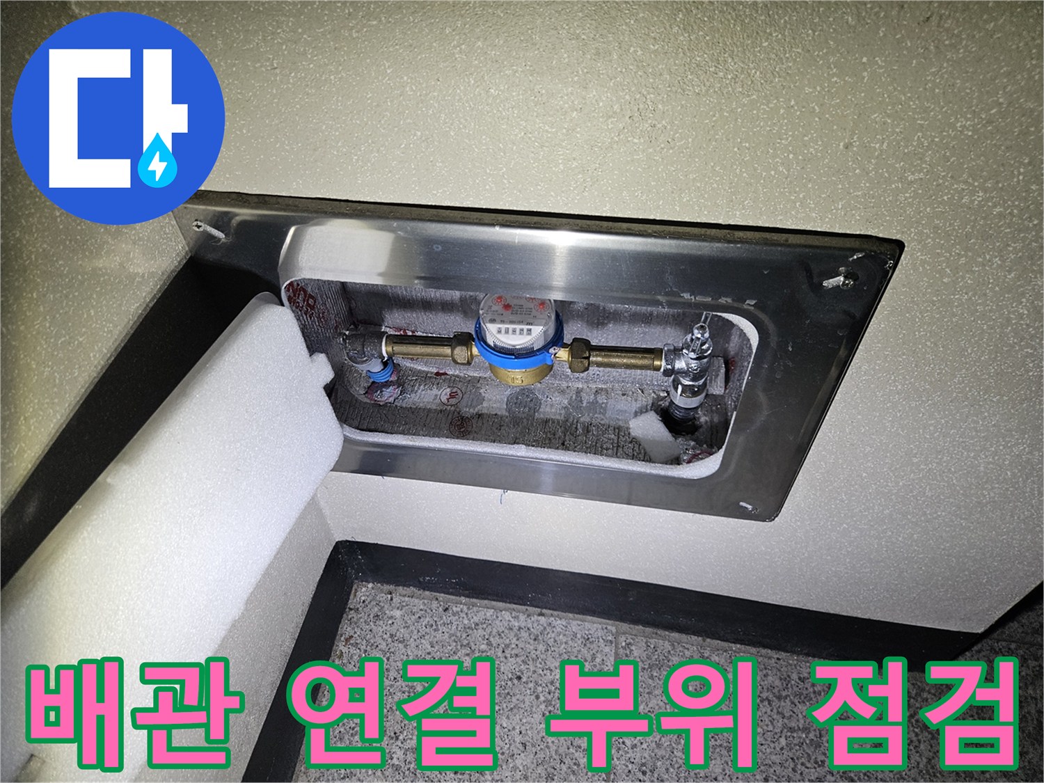 금속판 뒤에 위치한 수도 계량기와 밸브 장치