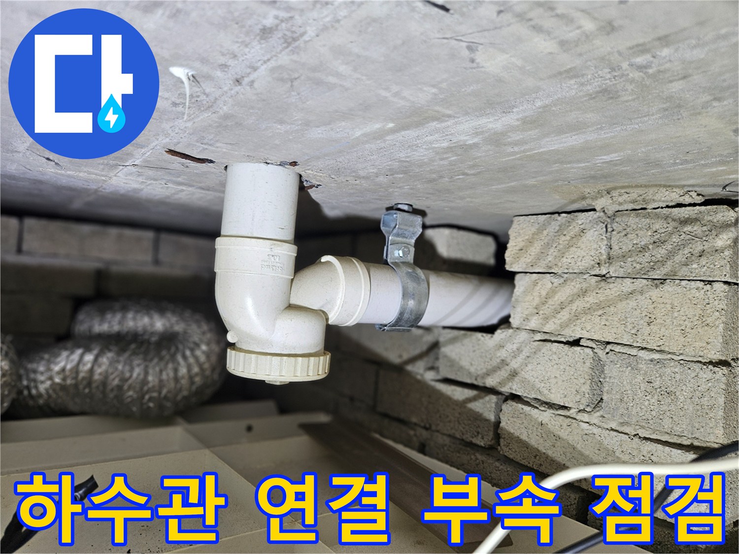 벽돌 벽면 사이로 노출된 하수 배수 배관의 보수 작업 모습
