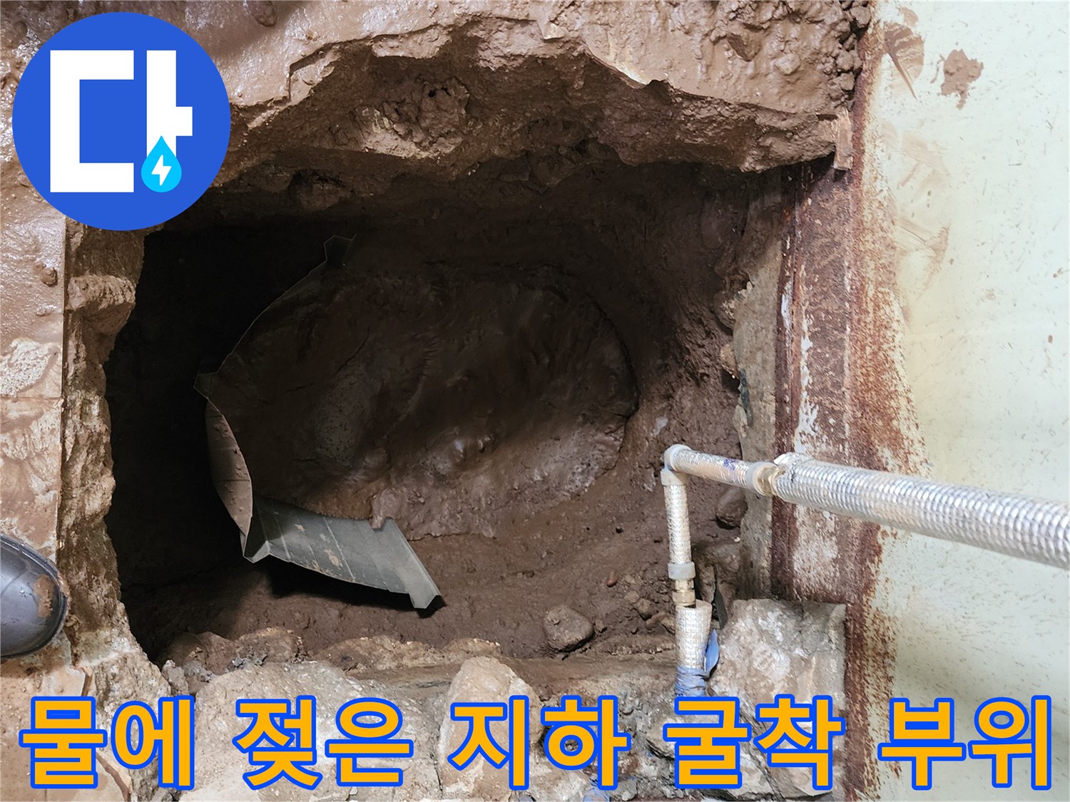 누수로 인해 물이 고여 있고 진흙이 가득한 지하 배관 작업 현장입니다.