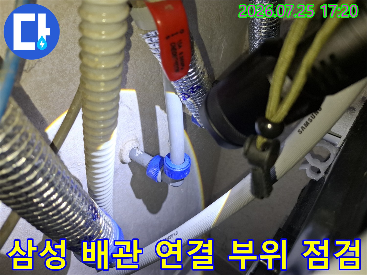 삼성 로고가 적힌 흰색 배관과 파란색 커넥터-적색 밸브 핸들이 보이는 누수 지점 사진