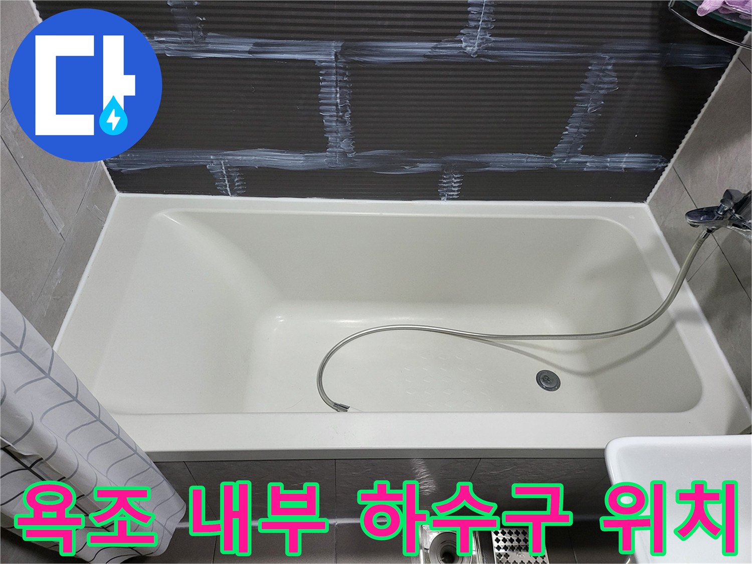 욕조 바닥 중앙에 위치한 배수구와 샤워 호스