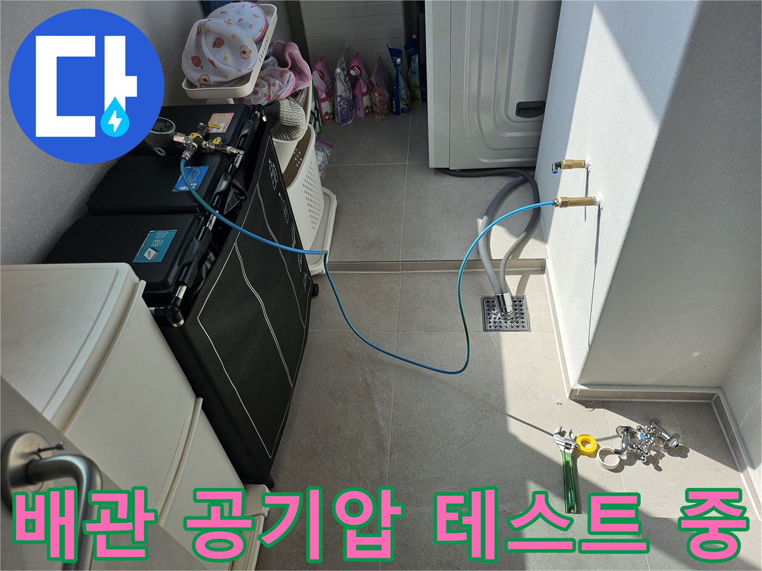 에어컨 배수 점검을 위해-벽면 배관에-공기압 장비를 연결한 모습