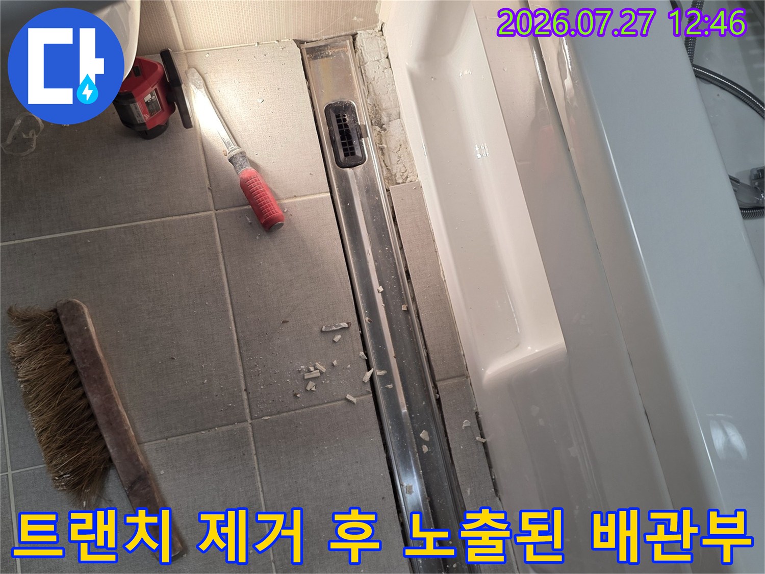 금속-재질의-트랜치가-제거되고-바닥-타일과-배관-연결부가-노출된-욕실-현장