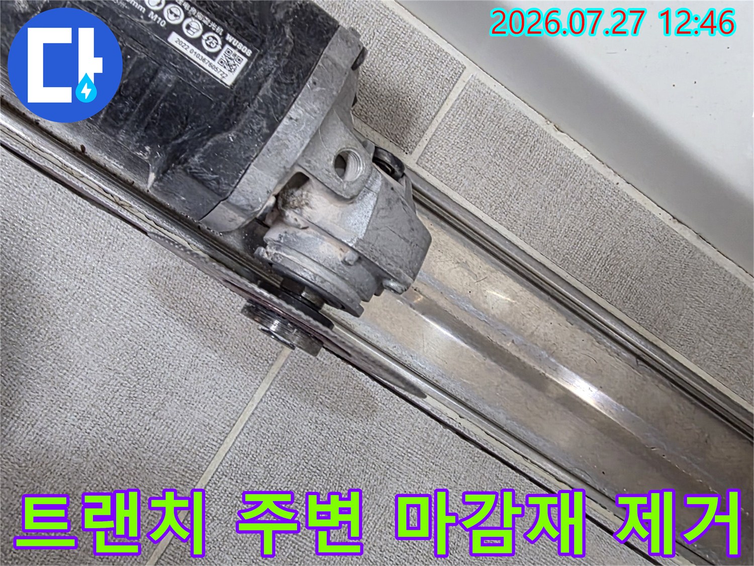 금속제 배수 트랜치와 타일 경계면을 전동 공구로 정밀하게 절삭하고 있는 사진