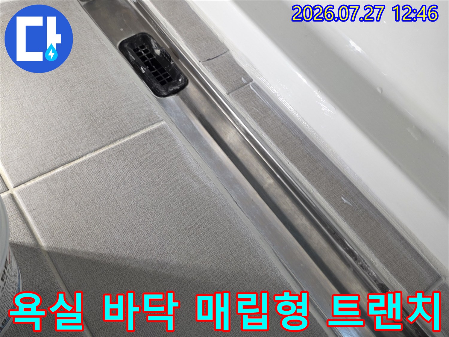 욕실 하단에 설치된 금속-트렌치 배수구와 주변 타일의 연결 부위