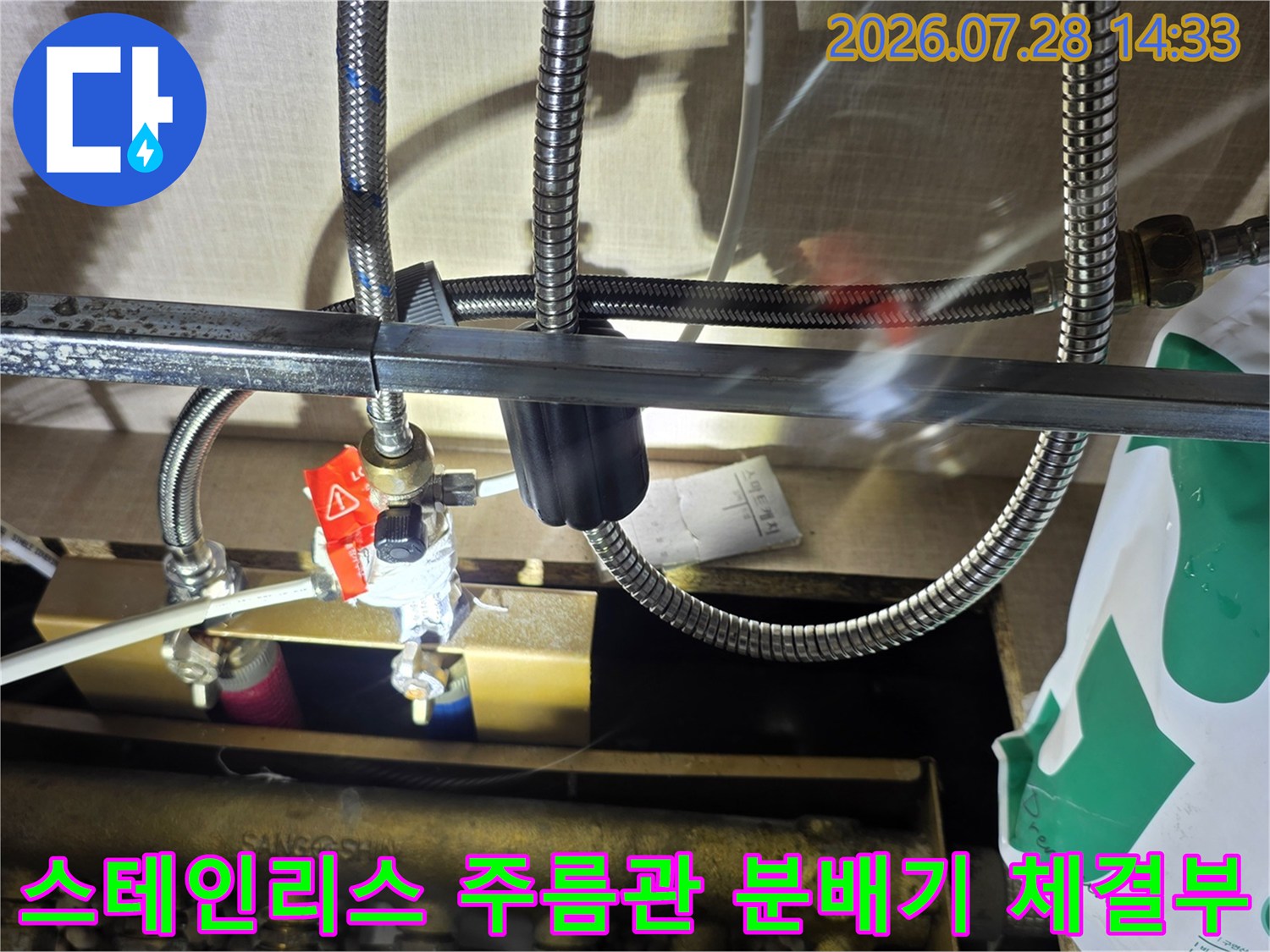 은색의 유연한 스테인리스 호스가 빨간 밸브 분배기에 연결되어 있는 배관 모습