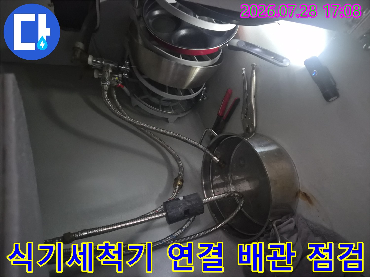 싱크대 하부 공간에서 식기세척기 연동 배관의 누수 여부를 꼼꼼하게 살피는 장면