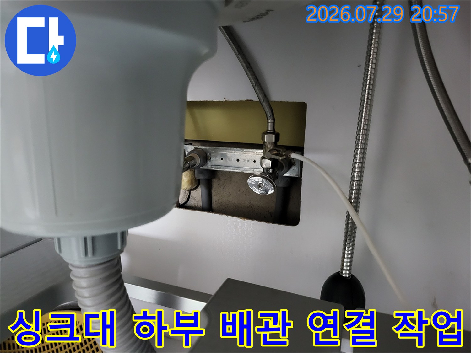싱크대 하단부에 위치한 온수 배관을 수선하고 있는 전문 기술자의 모습입니다.