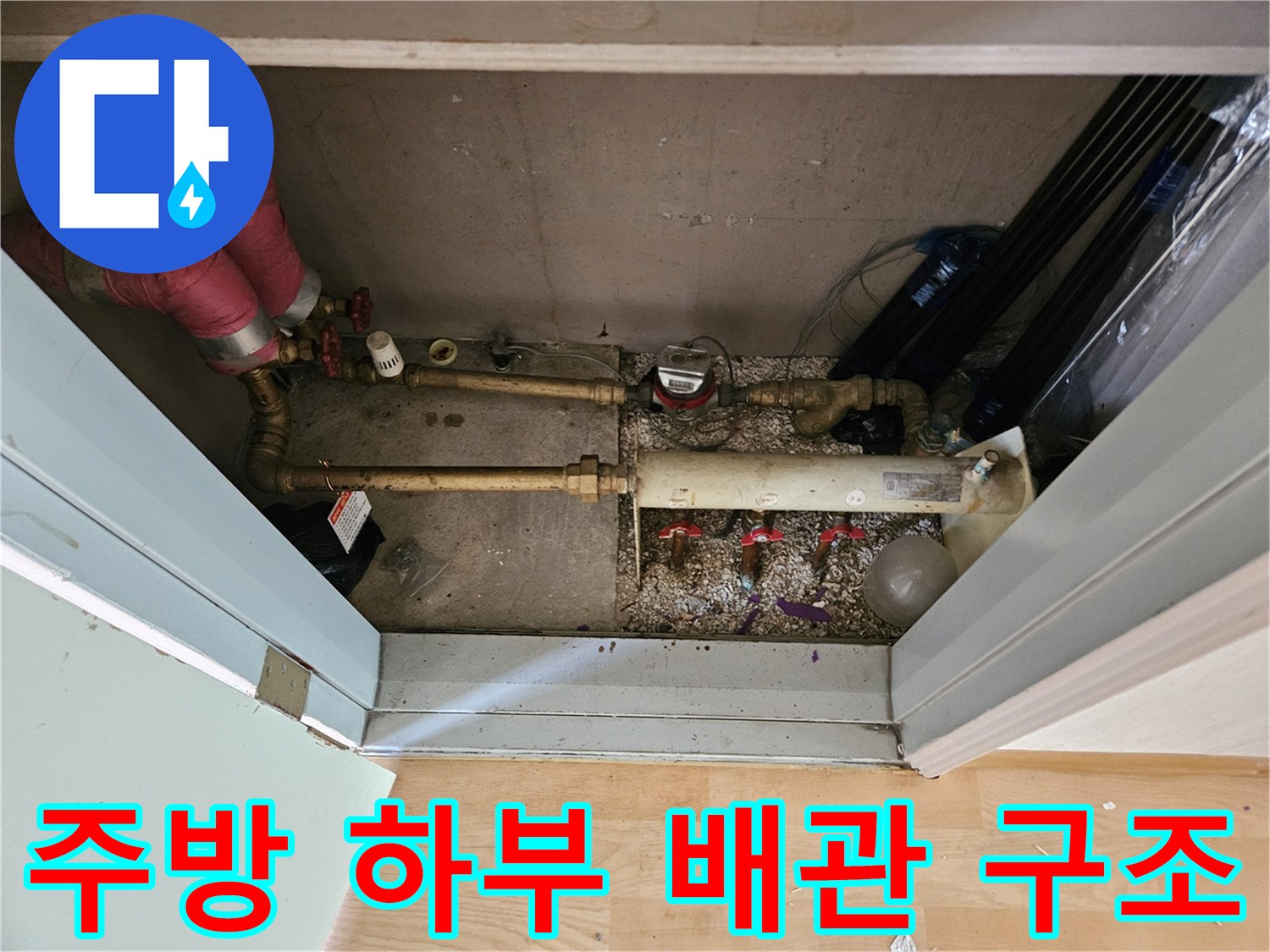 싱크대 아래 금속 관과 보온재가 씌워진 복잡한 배관들