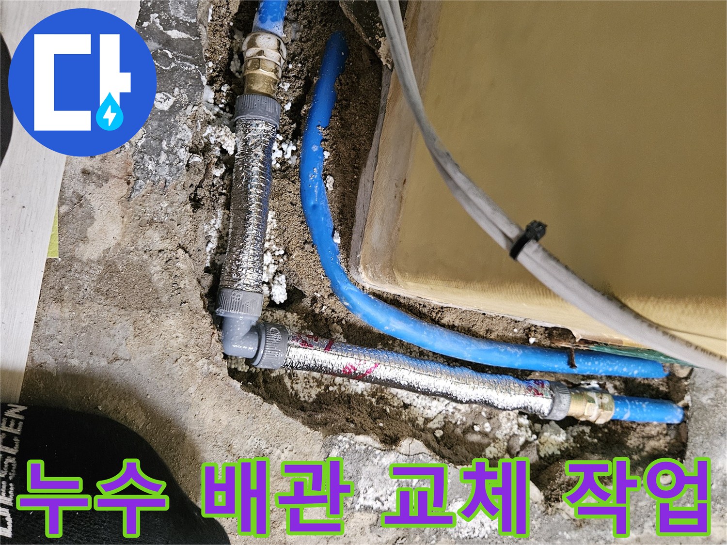 콘크리트 층 아래에 노출된 파란색 수도 배관의 연결 부위 수리