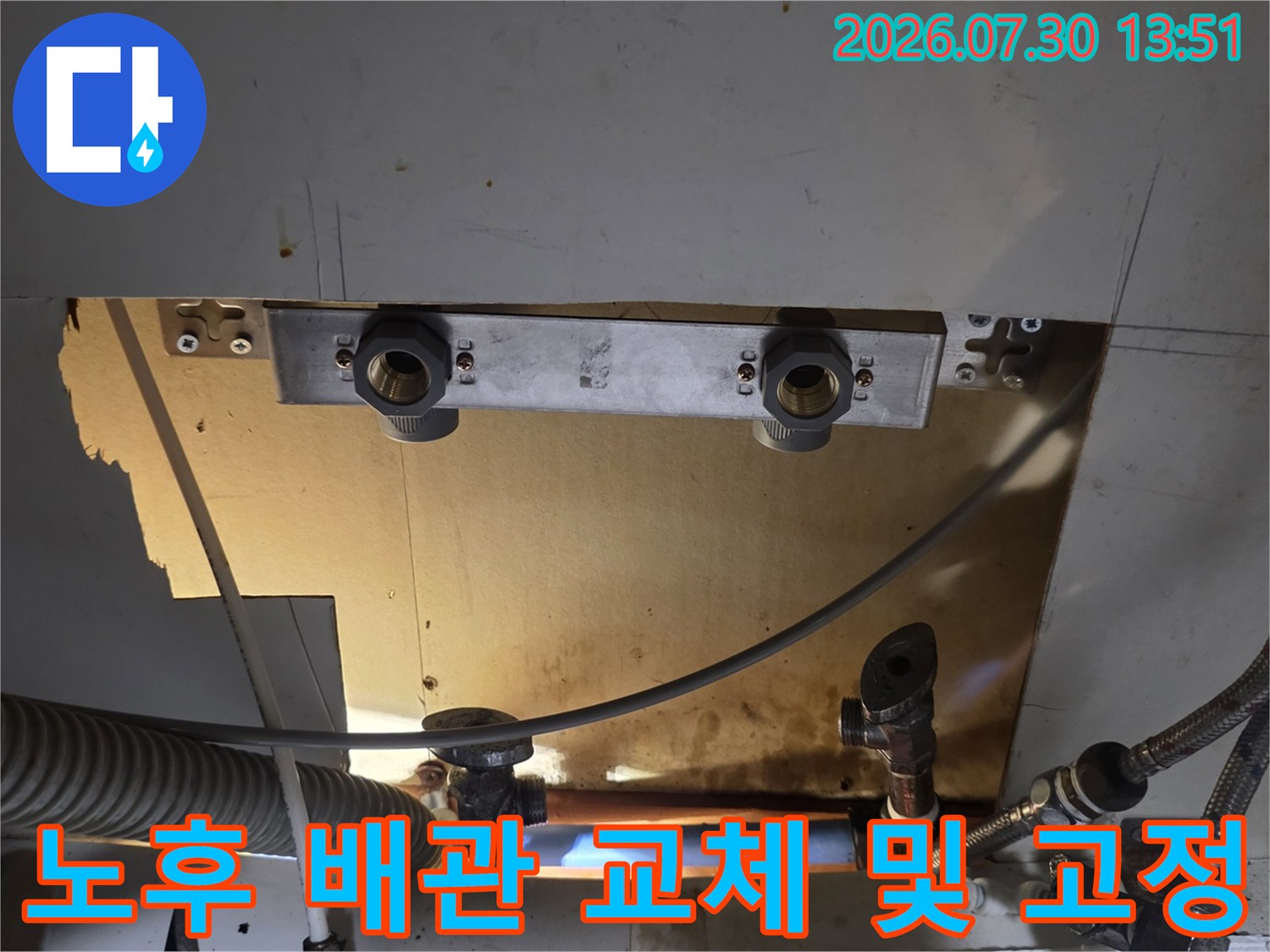 싱크대 하단에 노출된 급수 밸브와 스테인리스 주름관을 정비하는 장면