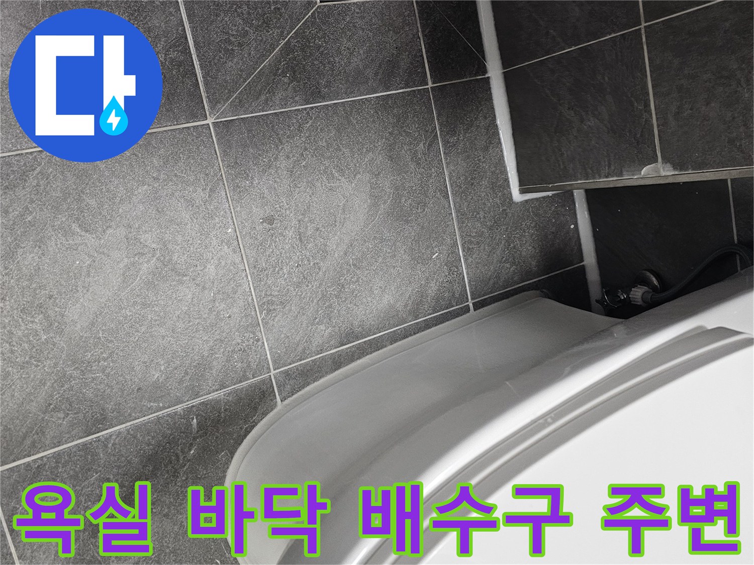 양변기 아래쪽 타일과 배수구의 근접 촬영
