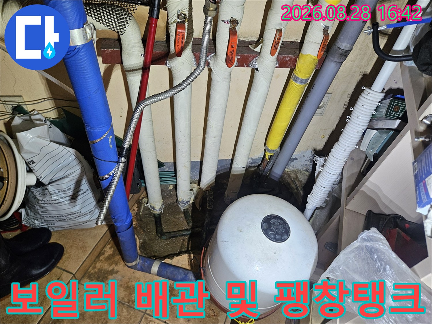 하얀색 팽창탱크와 다채로운 색상의 보온재가 입혀진 배관들