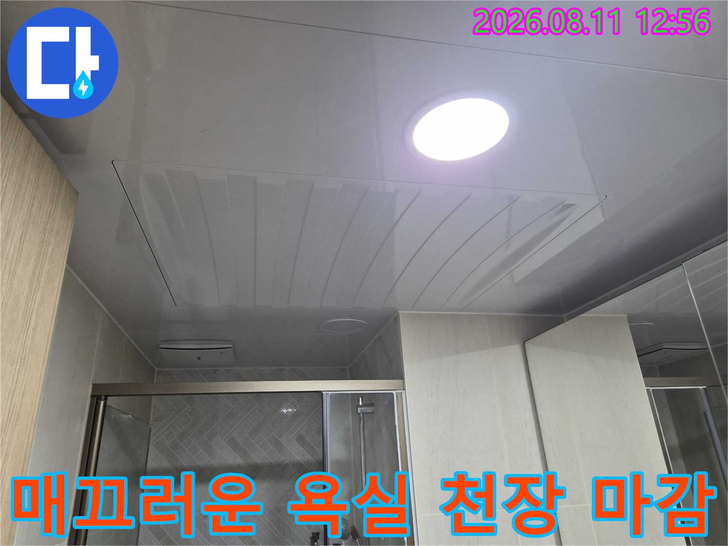 조명이 켜진 깨끗한 욕실 천장의 마감 상태를 보여줍니다.