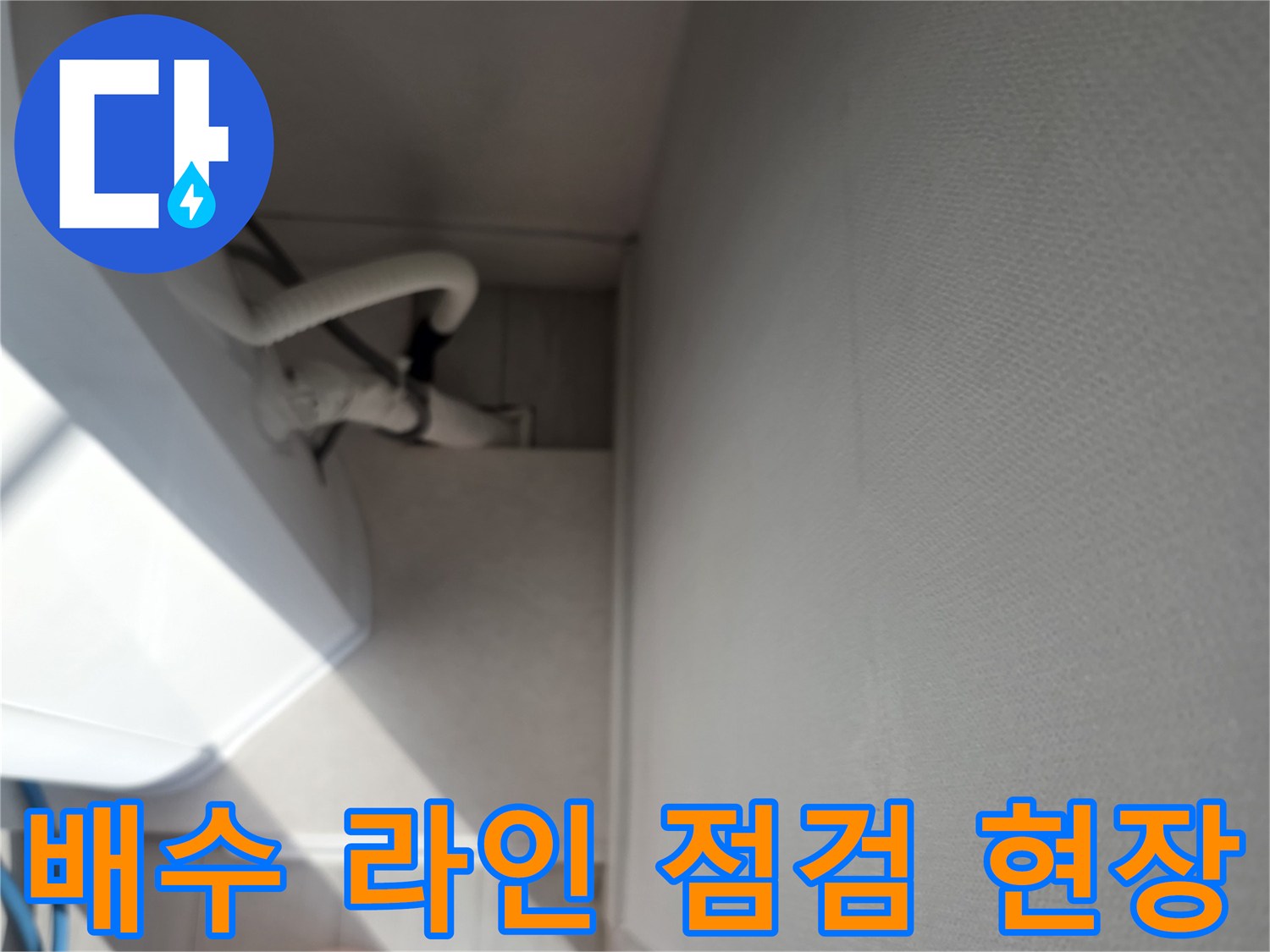 에어컨 배수 라인의 호스와 주변 마감재를 촬영한 사진입니다.