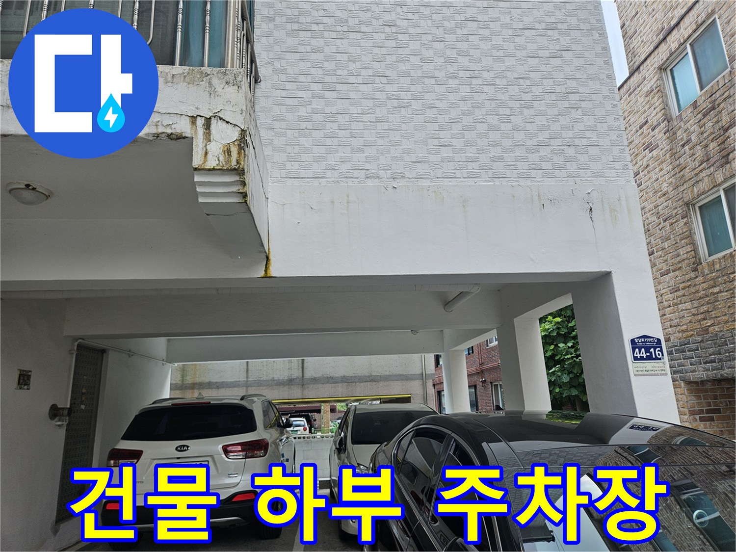 필로티 구조 건물 아래의 차량 주차 공간과 건물 외벽 전경