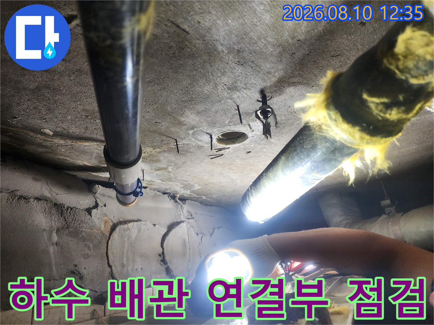 손전등으로 비춘 노후된 하수 배관과 주변 배관 구조물