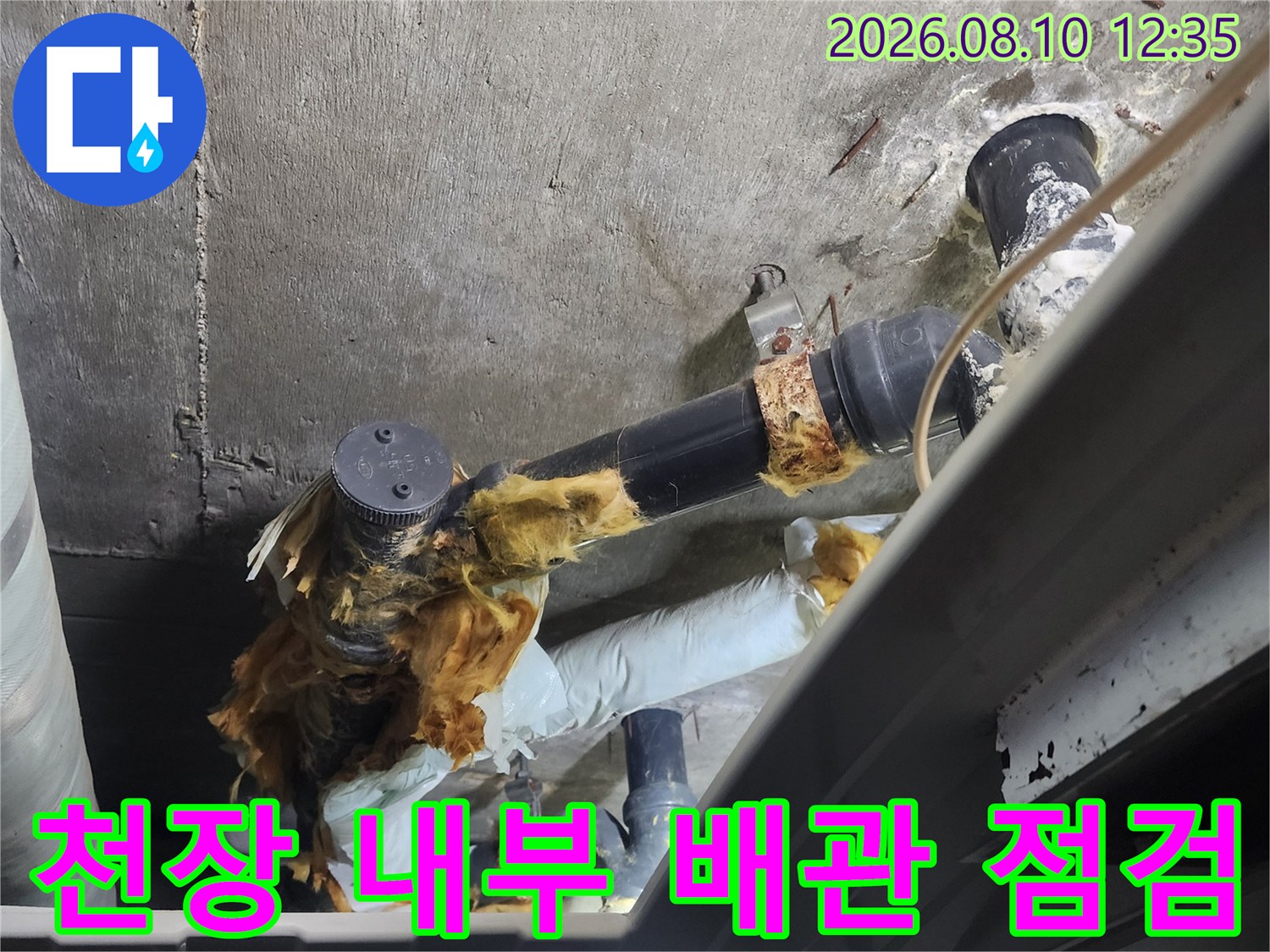 천장 안쪽에서 촬영한 - 하수 관로의 연결 부위와 마감재 상태입니다.