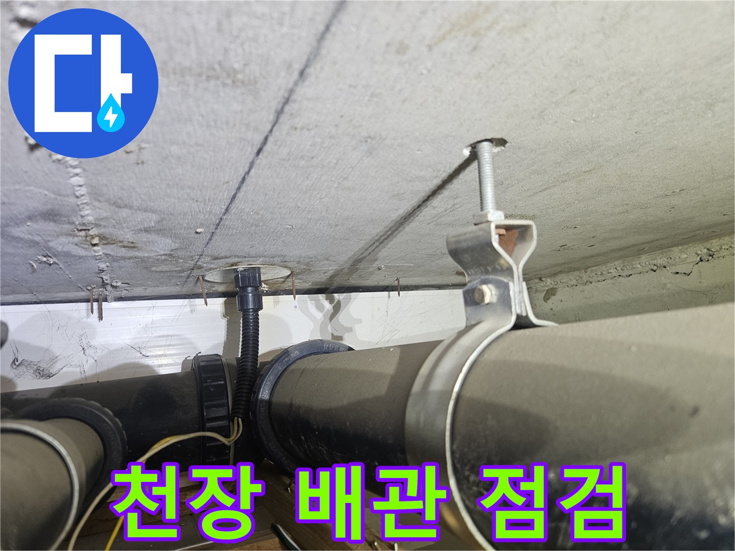아파트 천장에 설치된 검은색 배관과 지지대 모습입니다.