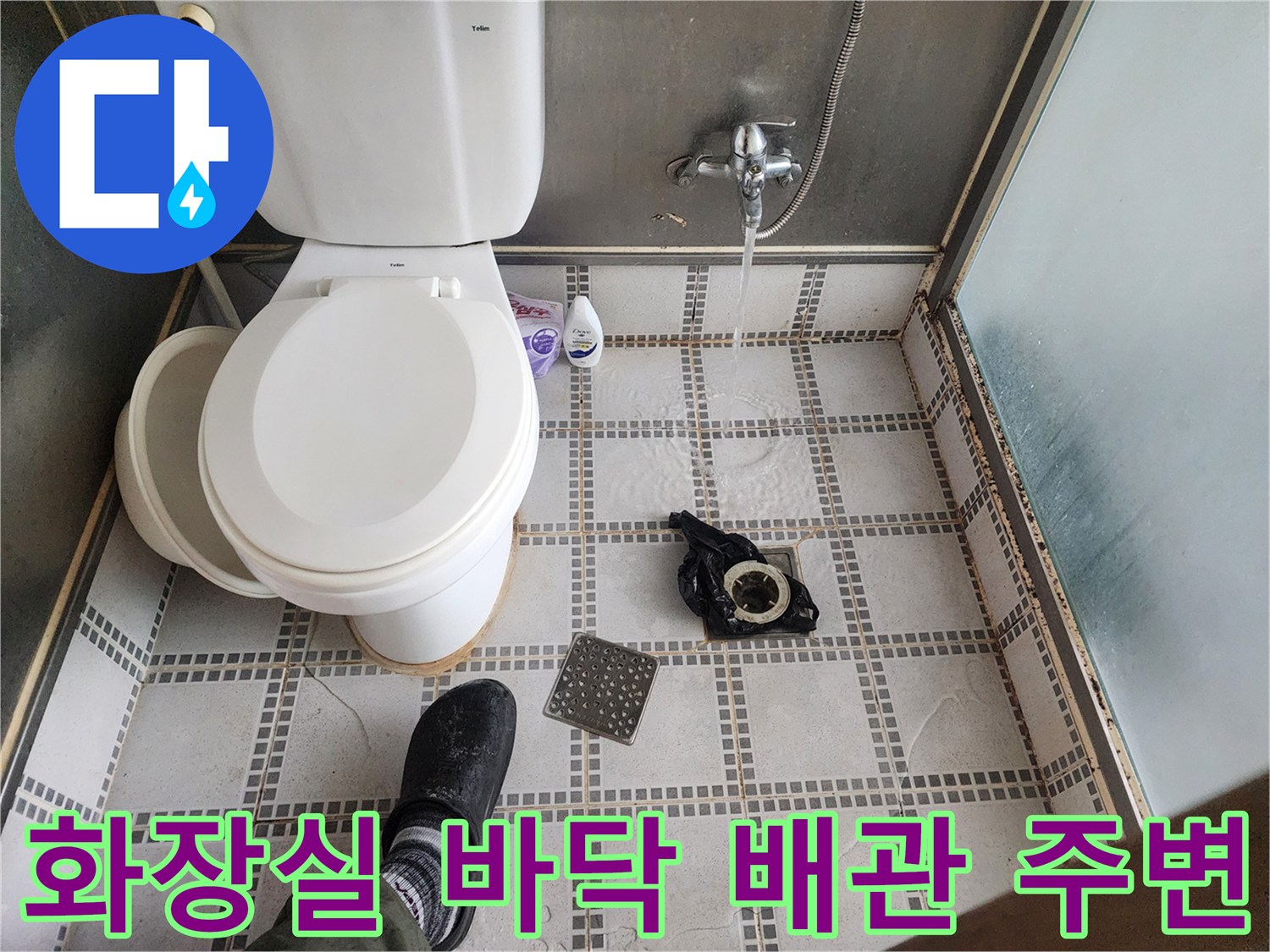 변기 뒤쪽 오수관 부근의 타일과 샤워기 수전이 보이는 화장실 내부