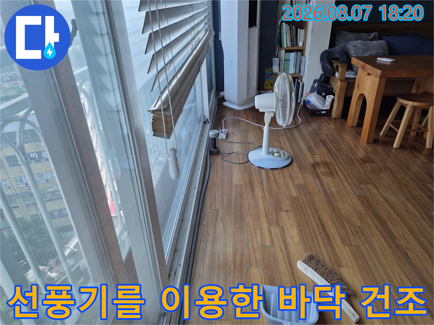 에어컨 배관 역류로 젖은 창가 마루를 말리기 위해 선풍기가 가동되는 모습