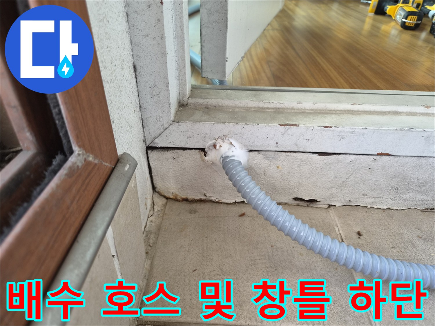 창틀 아래쪽 틈새로 연결된 회색 주름 배관 상태