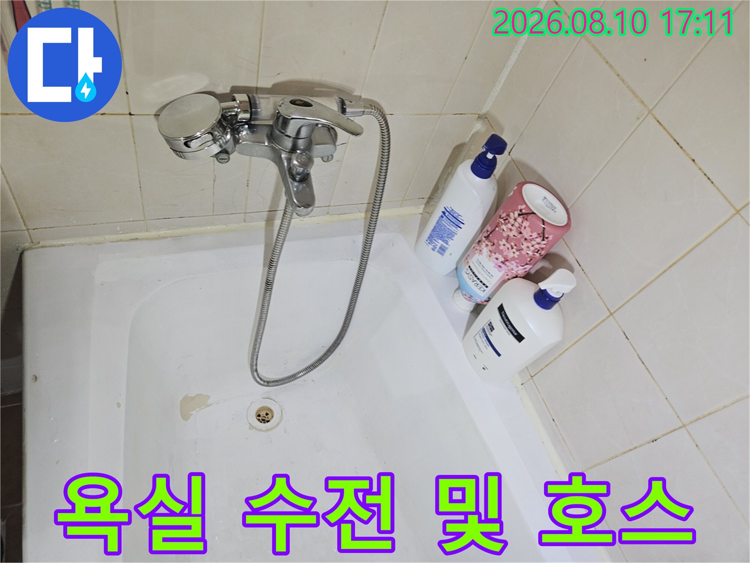 욕조에 설치된 샤워용 수전과 금속제 샤워 호스입니다.