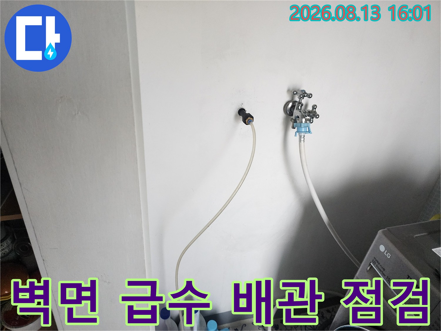 벽체에 노출된 수도 수전과 연결된 얇은 급수 호스의 모습입니다.