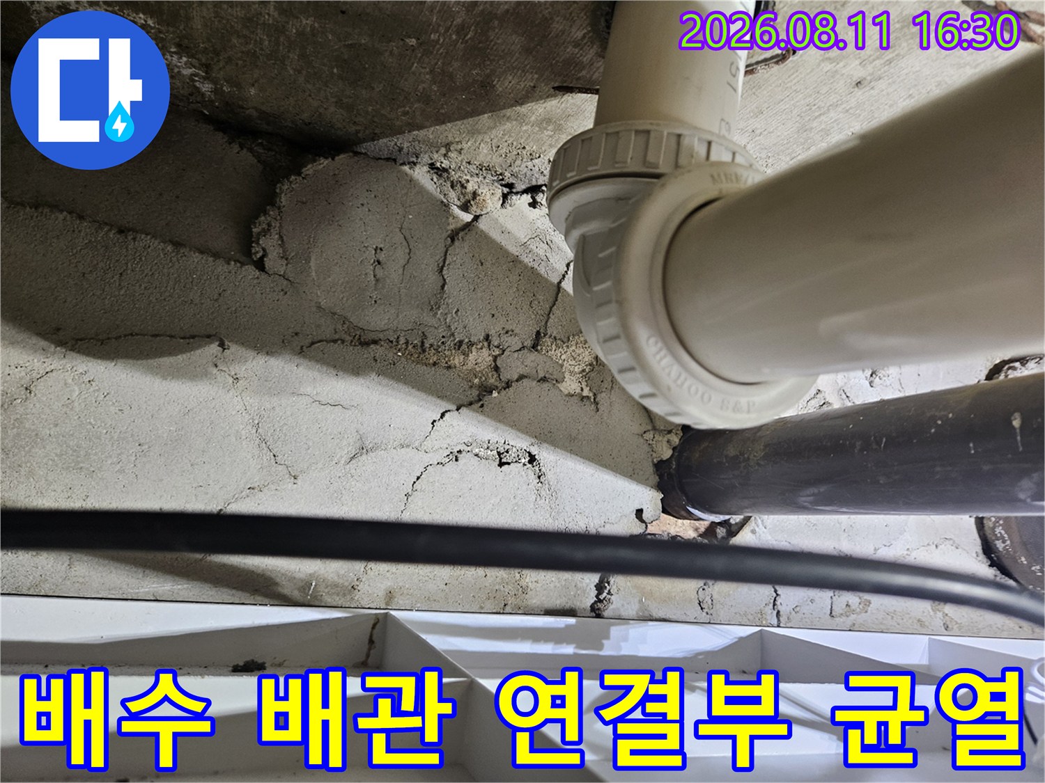 배수관 연결 지점의 콘크리트 틈새와 습기가 찬 마감재 상태