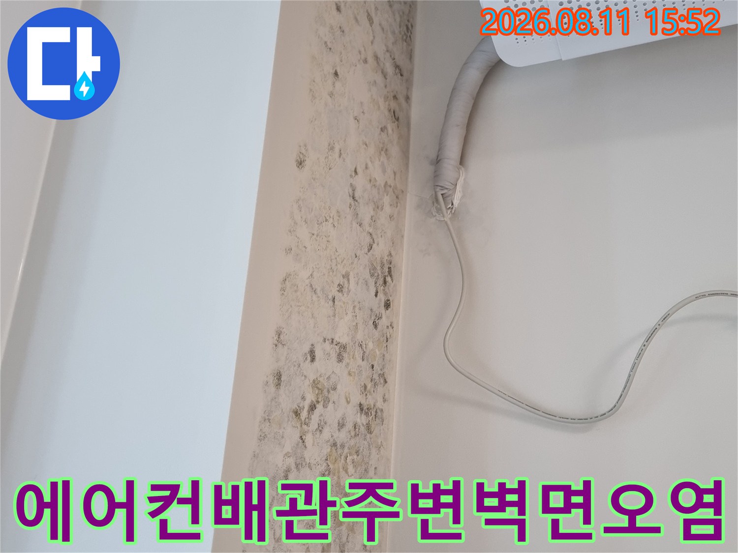 흰색 벽면에 형성된 갈색의 곰팡이 얼룩과 에어컨 드레인 배관이 연결된 모습