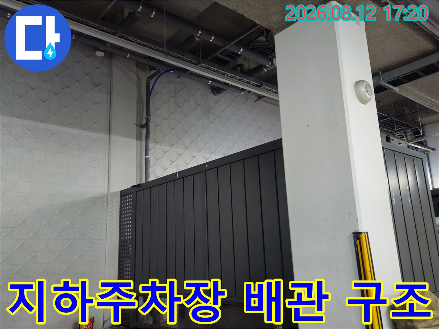 지하주차장 천장에 노출된 각종 배관과 설비 구조물을 보여주는 사진입니다.