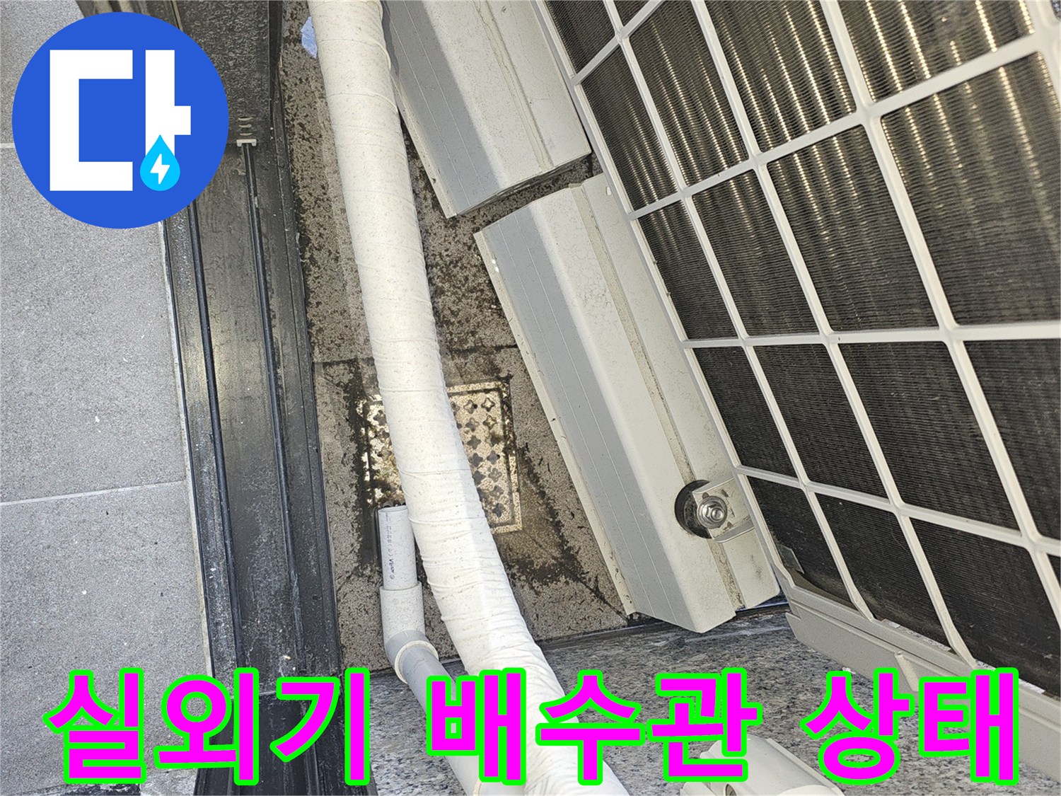 에어컨 실외기 뒤편의 배수 호스와 배관 연결 부위 모습입니다.