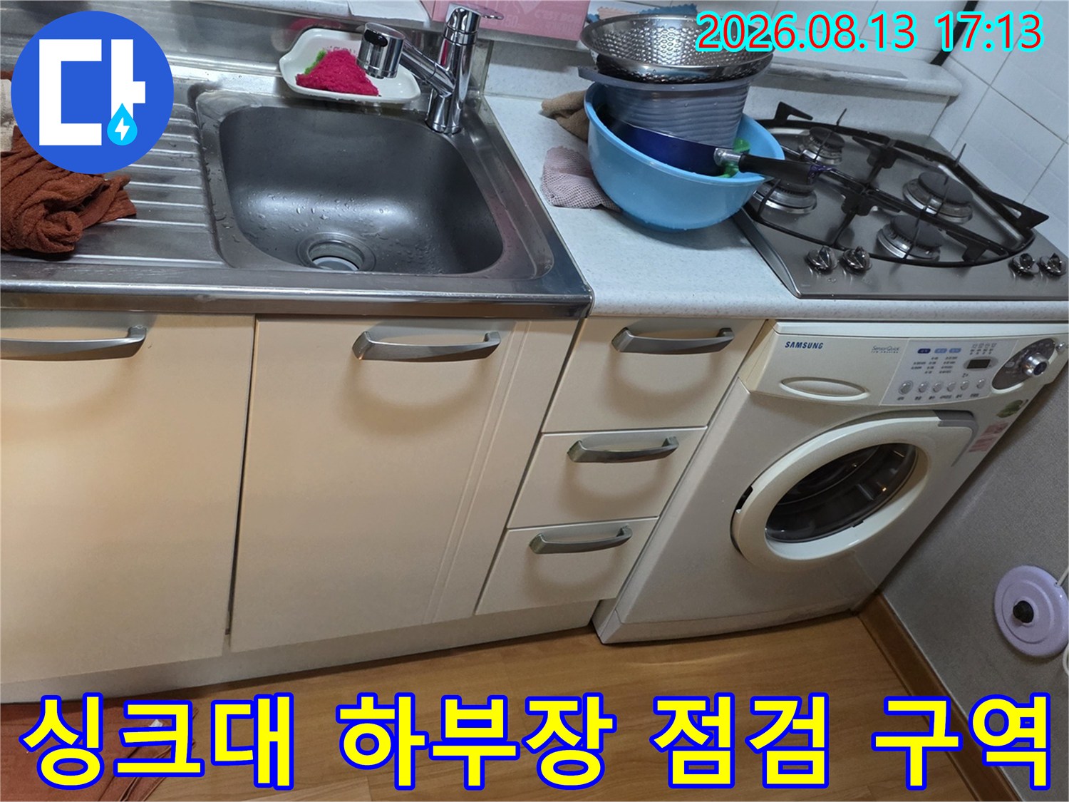 싱크대 아래쪽 수납장과 세탁기 공간을 촬영한 사진입니다.
