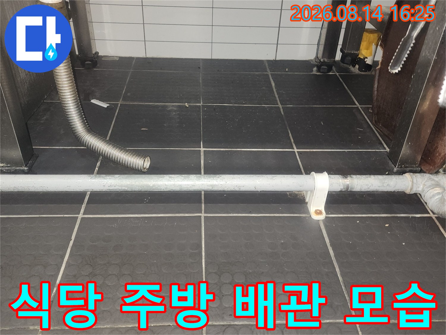 회색 타일 벽면에 설치된 금속 배관과 호스 연결 부위