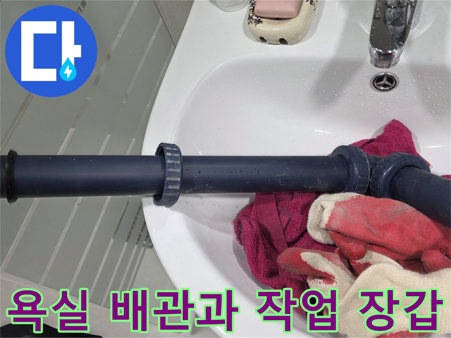작업용 장갑이 놓인 세면대 하부 배관 모습입니다.