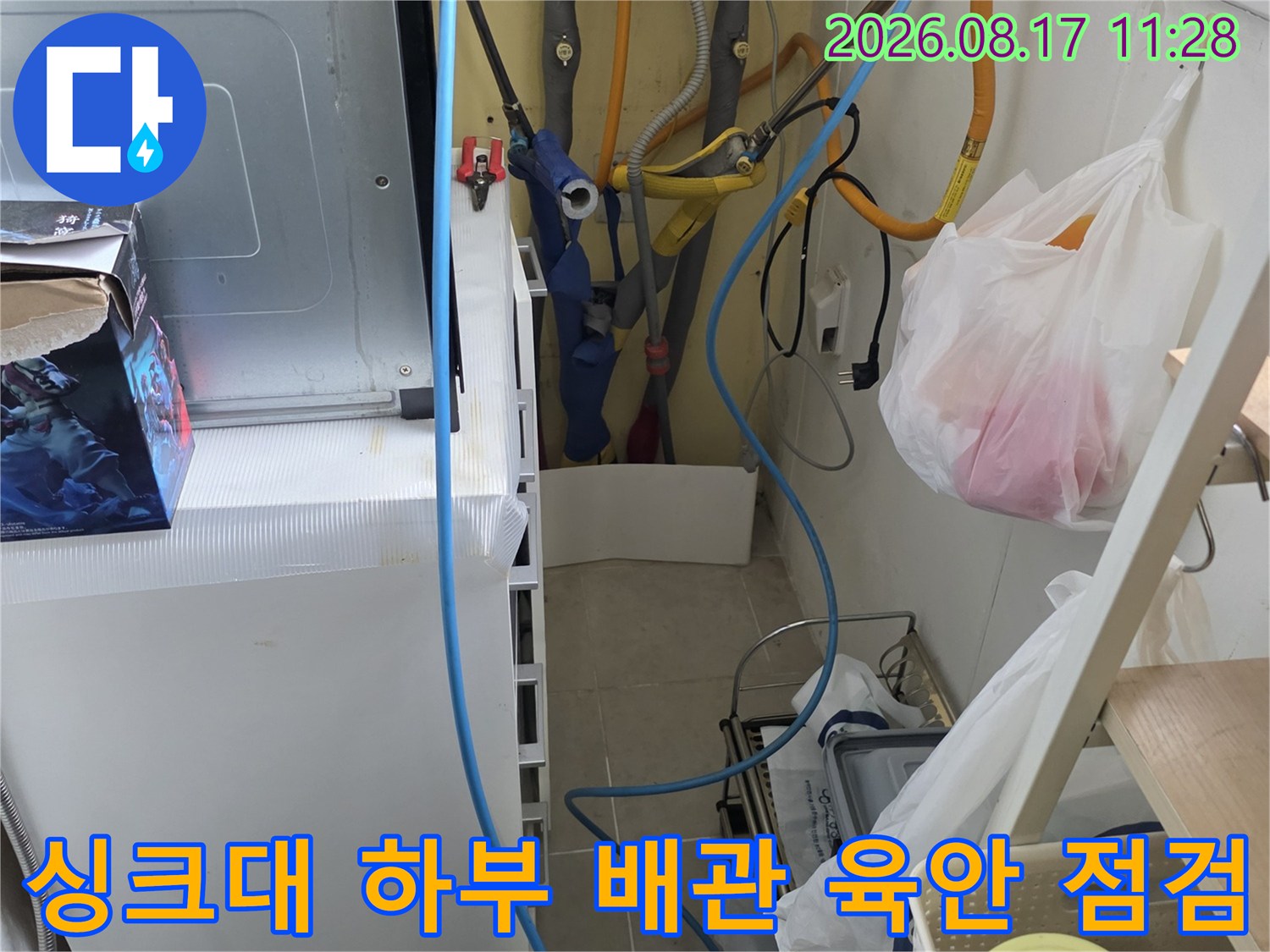 노란색 급수관과 파란색 정수기 호스가 연결된 싱크대 내부 모습