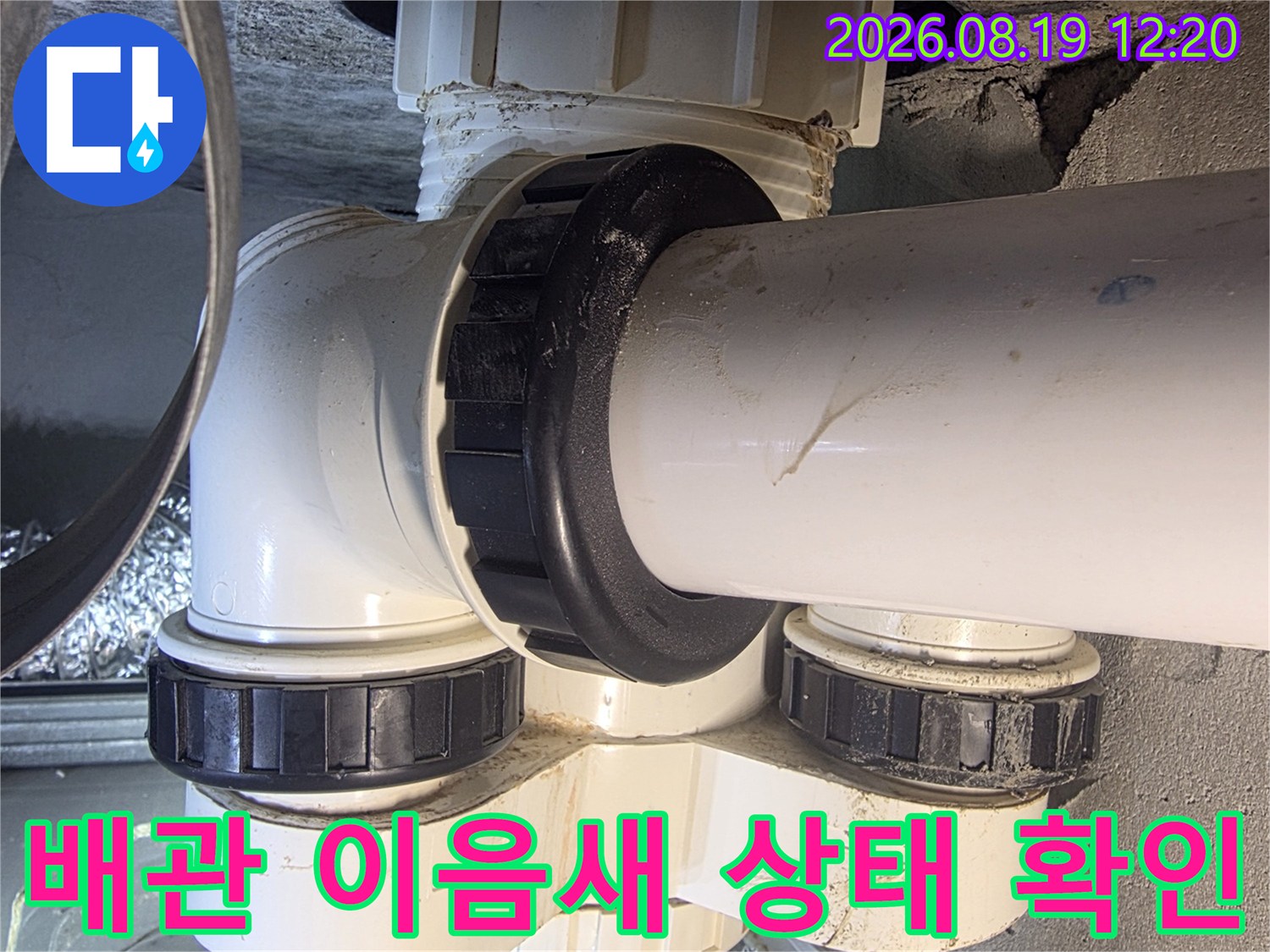 흰색 배관과 검은색 연결 커플링의 체결 상태를 세밀하게 관찰하고 있습니다.