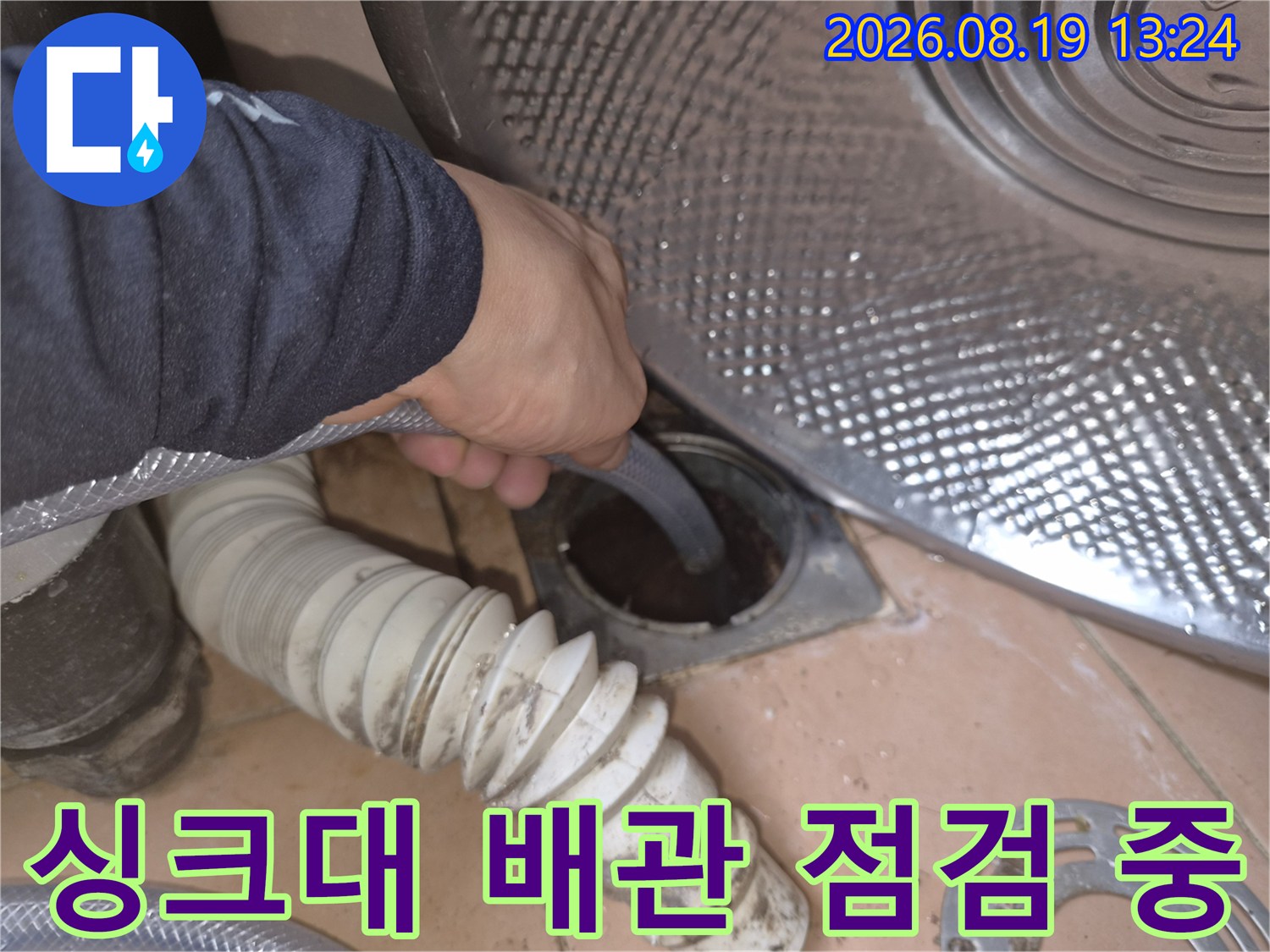 싱크대 하부장 아래쪽의 젖은 배관과 연결 부위를 엔지니어가 직접 확인하고 있습니다.