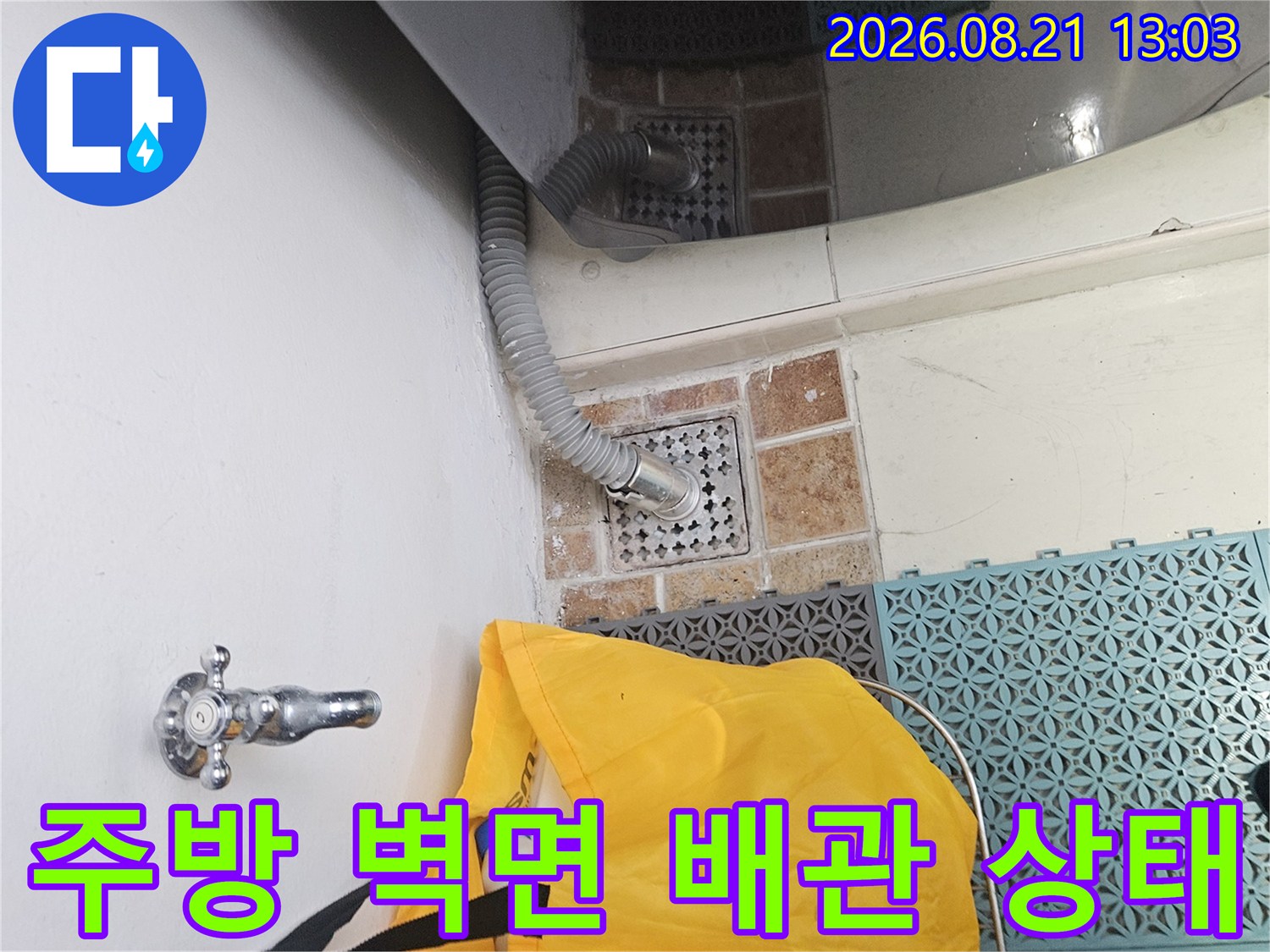 싱크대 아래쪽 타일 벽면에 설치된 수도 밸브와 배관의 모습입니다.