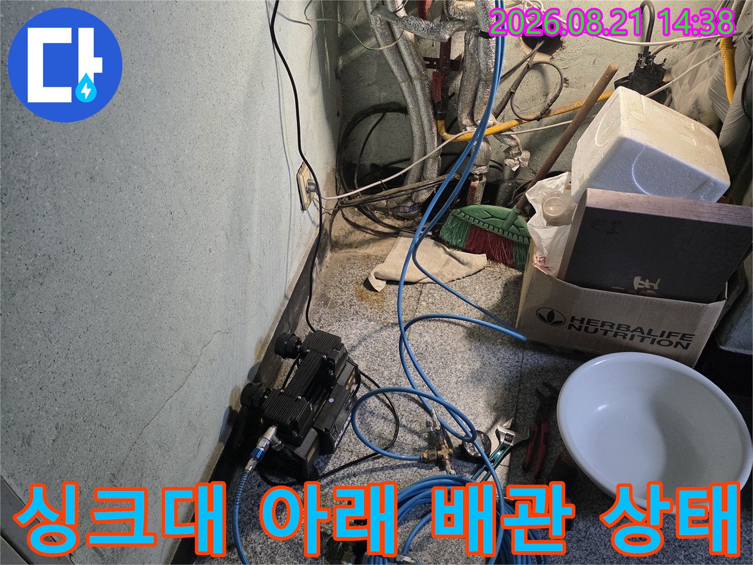 싱크대 하부의 복잡한 수도 배관과 탐지용 호스 모습입니다.