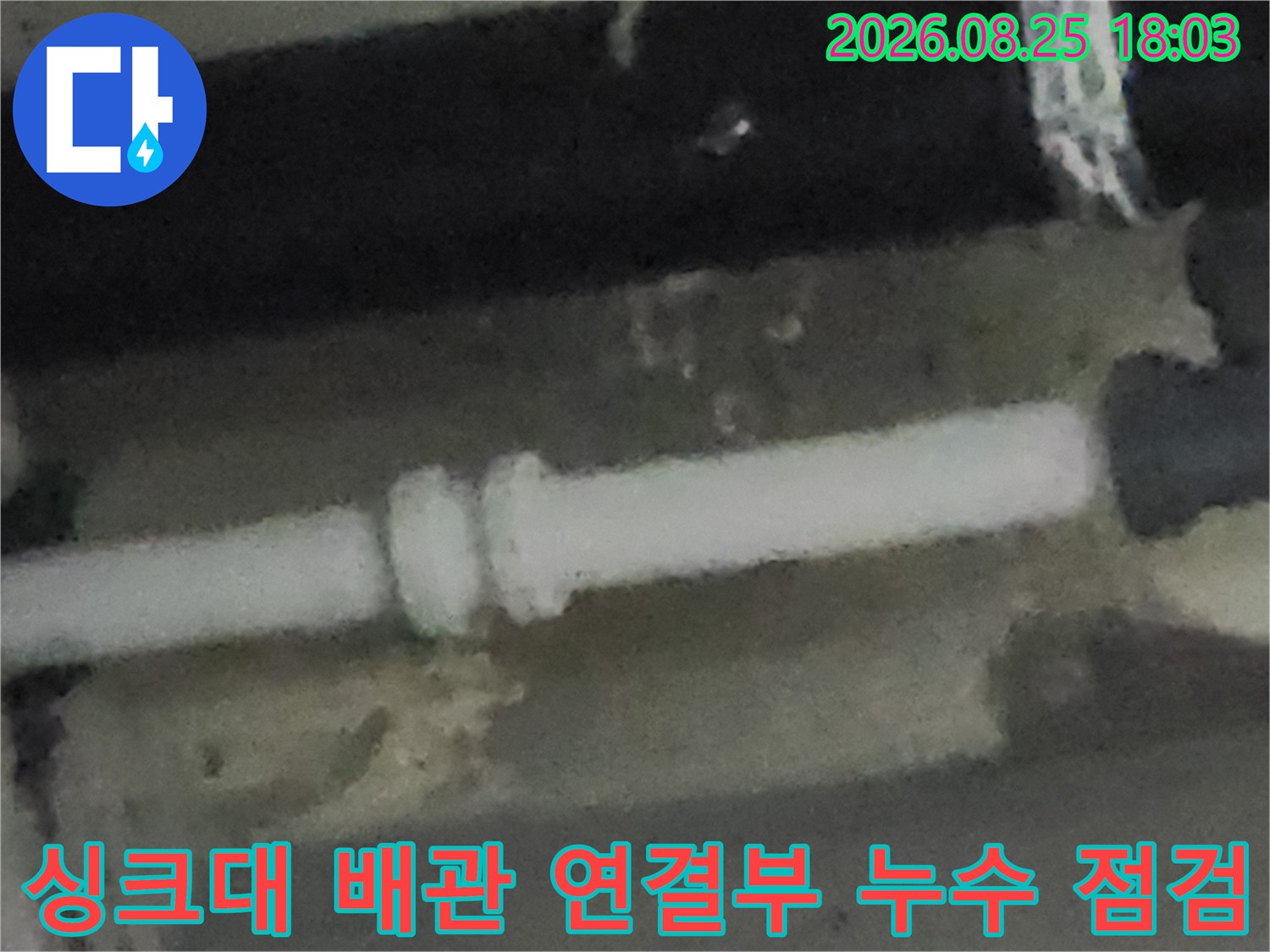 하얀색 배수 배관의 연결 부속 부분에 나타난 누수 현상을 촬영한 사진입니다.