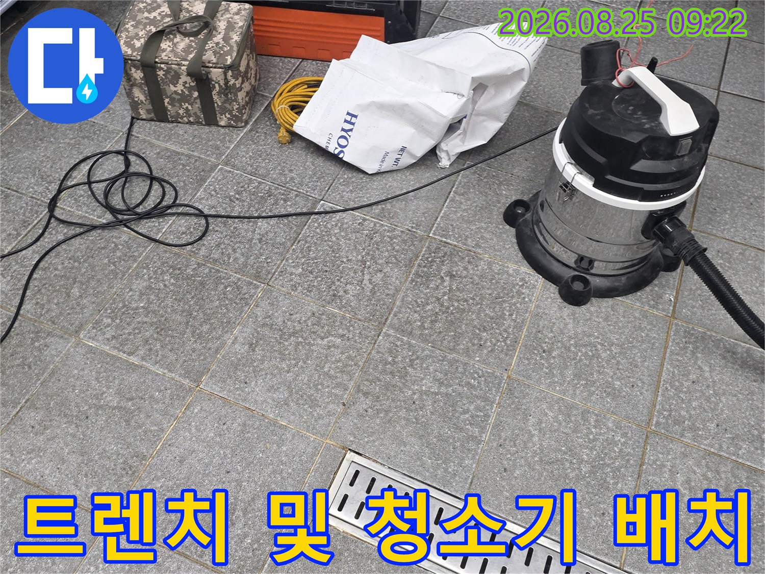 금속 트렌치 배수구와 작업용 청소기가 함께 찍힌 현장 사진입니다.