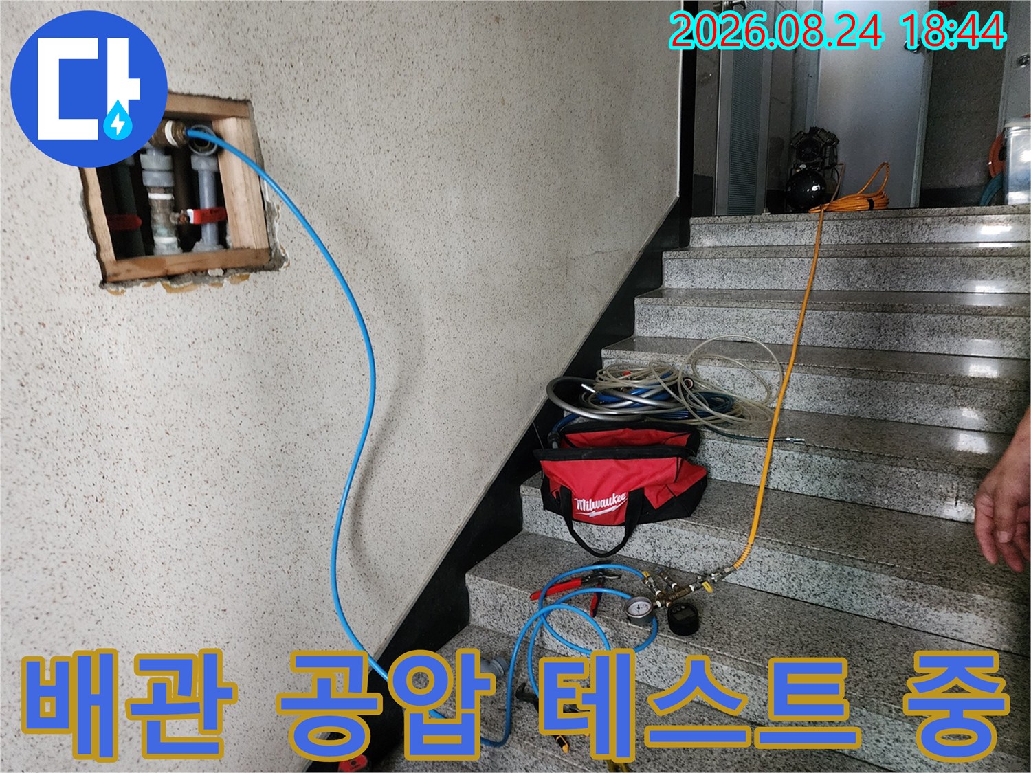 구로동 현장-벽체 노출 배관에 연결된 파란색 압력 호스