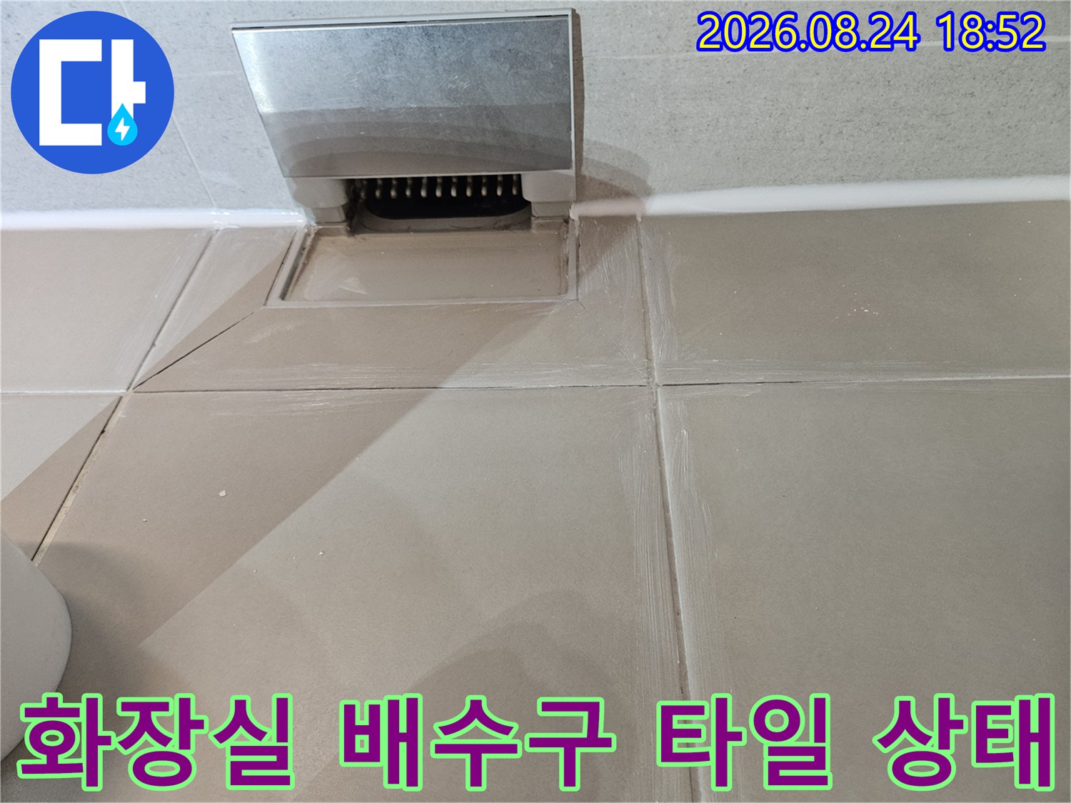 성북구 장위동 화장실의 베이지색 타일과 금속 재질의 배수구 덮개 모습입니다.