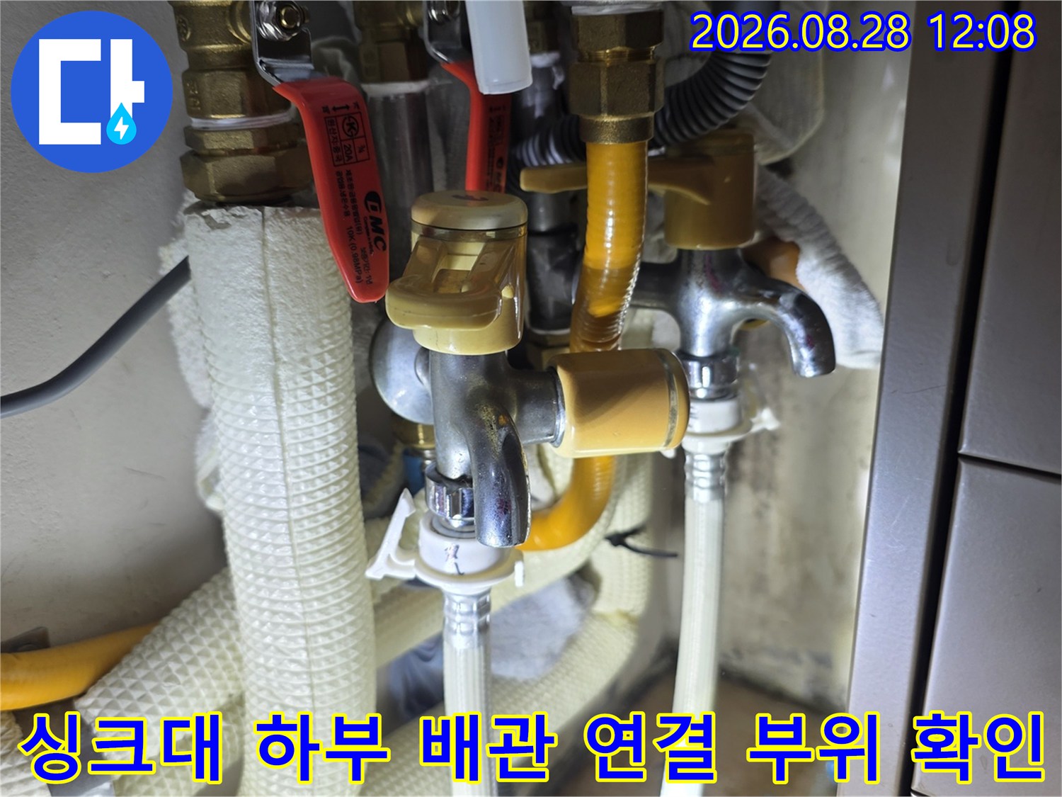 싱크대 하단 금속 밸브와 노란색 보온재로 감긴 배관의 상세 모습