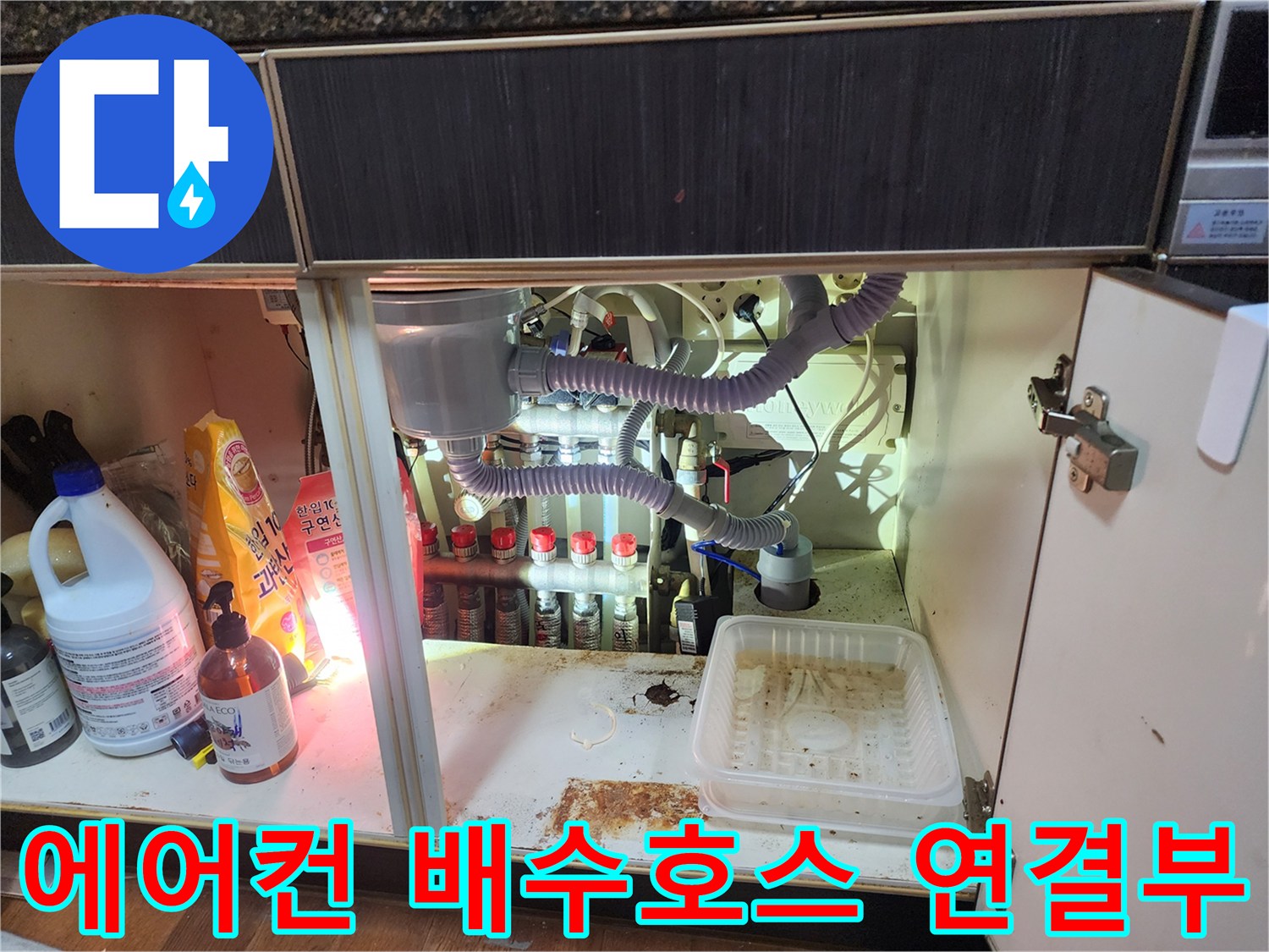 싱크대 하부장 내부의 굴곡진 에어컨 배수 호스와 배관 연결 상태