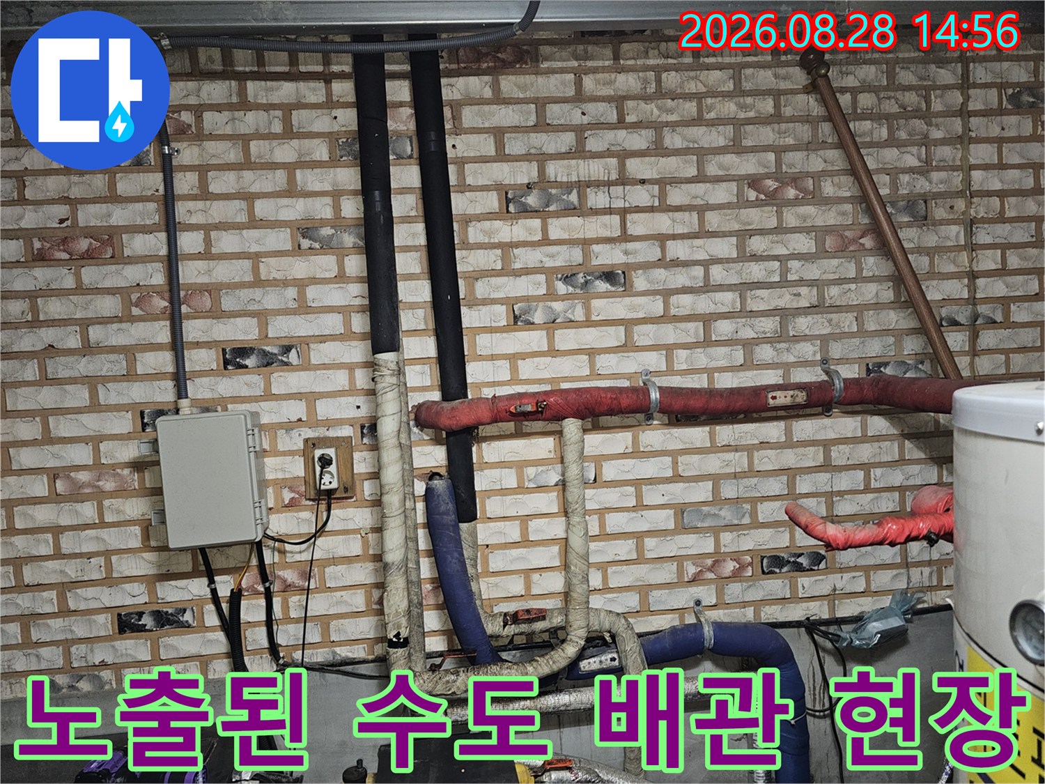 벽돌 벽면에 설치된 붉은색과 파란색 보온재가 씌워진 배관들