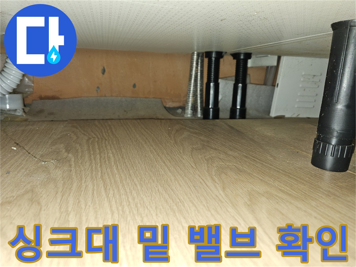 싱크대 아래쪽 보온재가 씌워진 배관과 검정색 제어 밸브의 근접 촬영