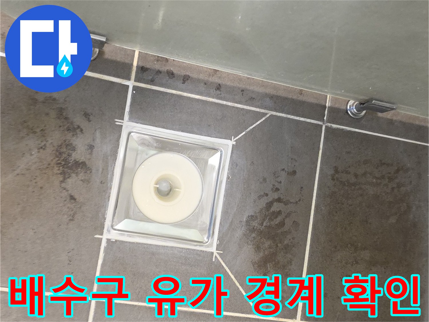 화장실 배수구 부근의 타일과 유가 접합부를 근접 촬영한 모습
